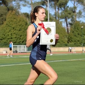 UK university student athlete training on campus sports field while holding scholarship award certificate